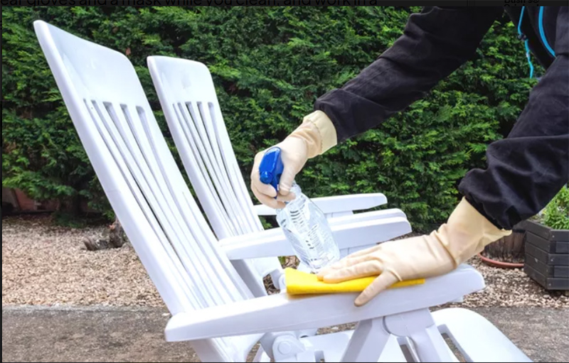 Cleaning outdoor patio furniture with a spray and cloth.